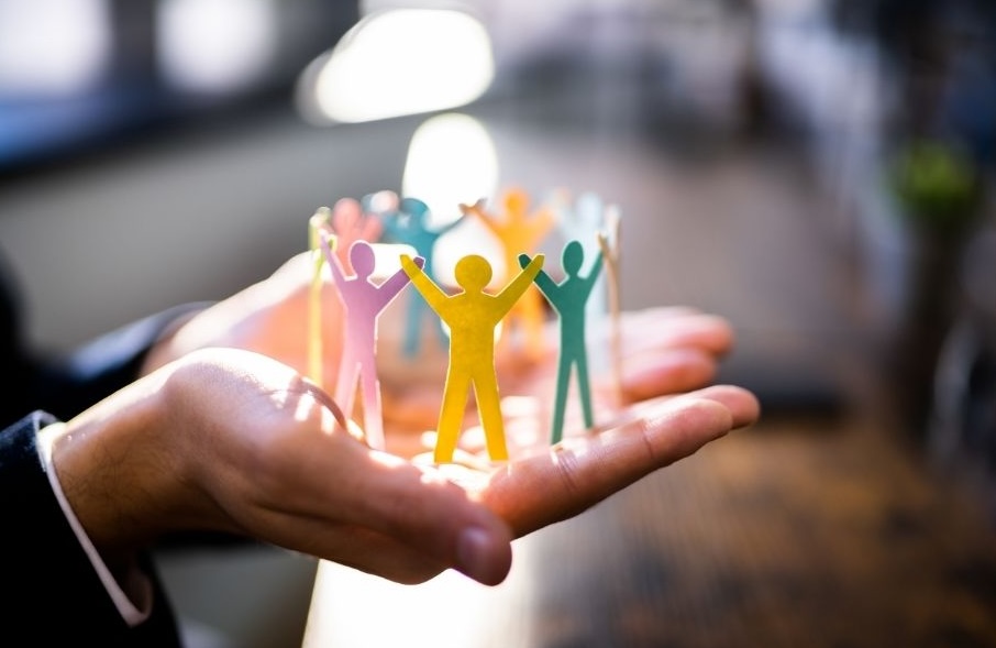 Hands holding paper people, representing how a leader cares for their team.
