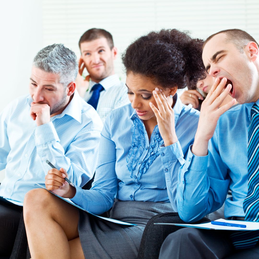 group of employees looking bored and distracted during a presentation