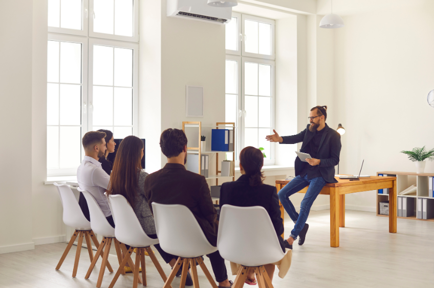 A business leader is standing in front of their team teaching to ensure training translates into real-world results