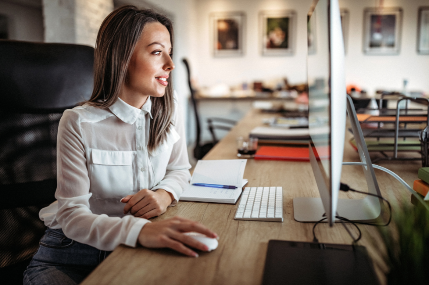 business woman sits at her computer writing reviewing policy and procedure documents